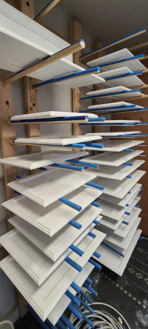 Freshly sprayed cabinet doors drying on a rack