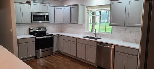 Kitchen cabinets refinished in warm gray with white subway tile backsplash