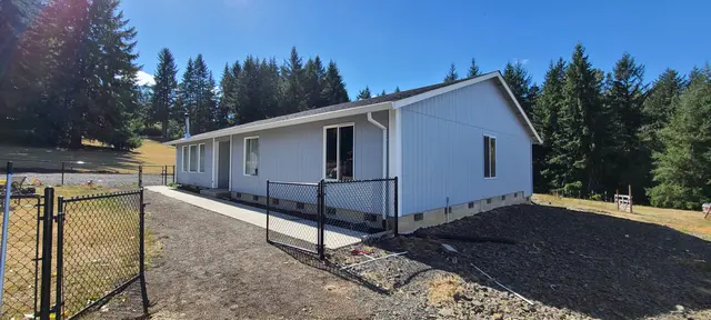 Newly painted gray-blue ranch home behind a black metal fence