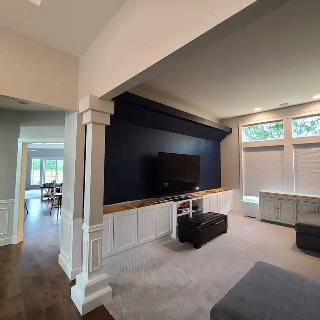 Navy blue accent wall above white built-in cabinets in a media room